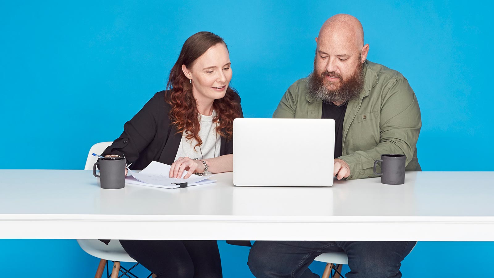 Couple sitting in front of a laptop, drinking coffee.